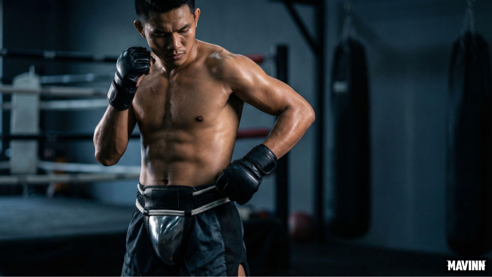 Muay Thai fighter in a boxing gym adjusting his traditional Thai steel cup groin protector