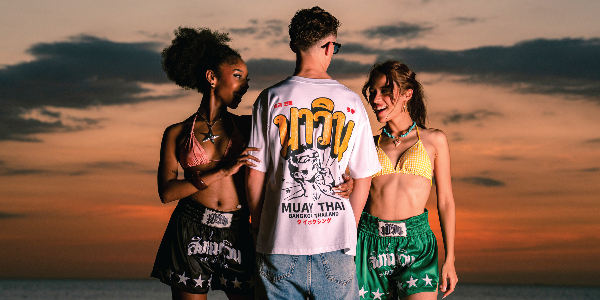 Three athletes wearing MAVINN Muay Thai shorts and streetwear at sunset - Born in the Ring, Built for Champions